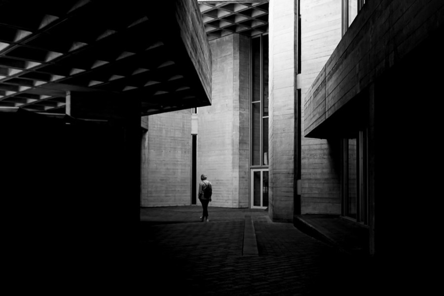 one person walking amongst shadow of buildings
