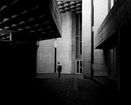 one person walking amongst shadow of buildings